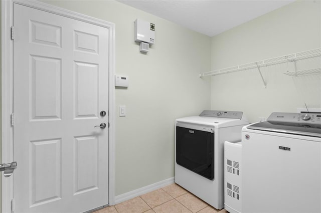 laundry area with laundry area, light tile patterned floors, baseboards, and washing machine and clothes dryer