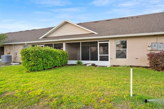 back of house with a yard, roof with shingles, central AC unit, and stucco siding