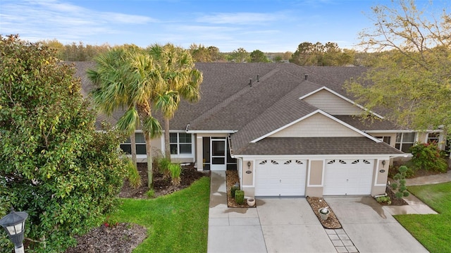 view of front of home with a front lawn, roof with shingles, stucco siding, a garage, and driveway