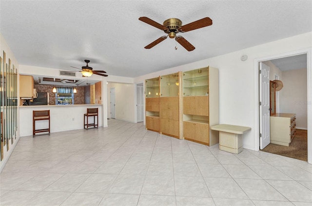 unfurnished living room featuring visible vents, a textured ceiling, and ceiling fan