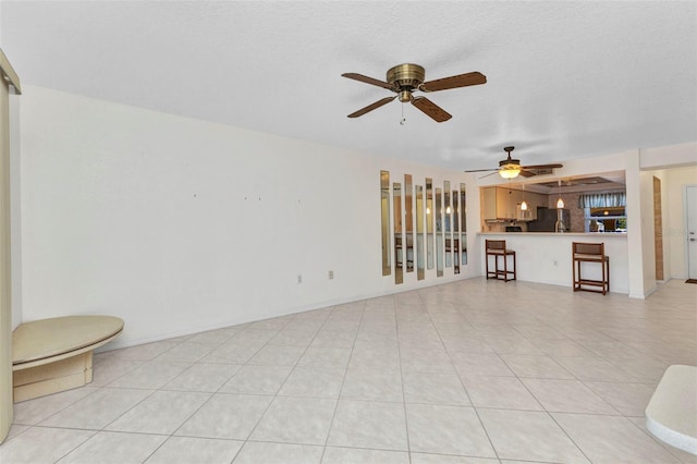 unfurnished living room featuring baseboards, ceiling fan, and light tile patterned flooring