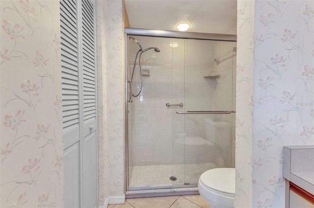 full bathroom featuring tile patterned floors, toilet, a stall shower, a closet, and wallpapered walls