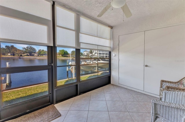 unfurnished sunroom featuring a ceiling fan and a water view