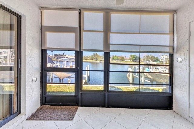 interior space featuring a water view, a textured wall, and tile patterned floors