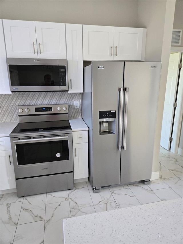 kitchen featuring visible vents, marble finish floor, white cabinets, and stainless steel appliances