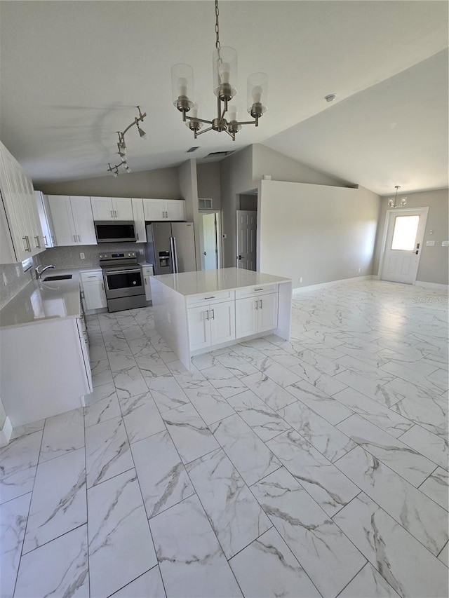 kitchen with a center island, open floor plan, lofted ceiling, stainless steel appliances, and a sink