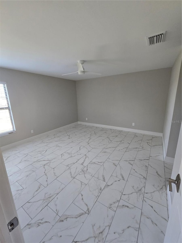 unfurnished room featuring a ceiling fan, visible vents, marble finish floor, and baseboards