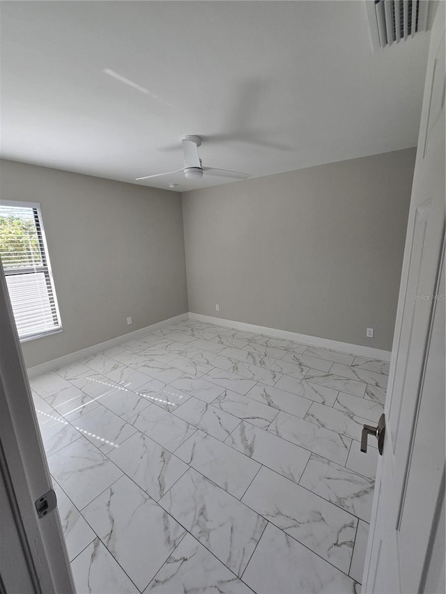 empty room with visible vents, baseboards, marble finish floor, and ceiling fan