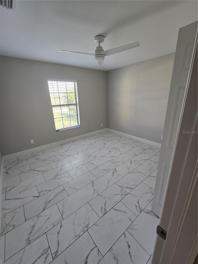 spare room with visible vents, marble finish floor, a ceiling fan, and baseboards