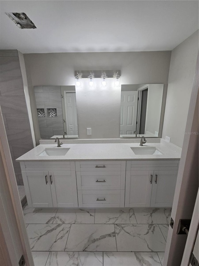 bathroom with double vanity, marble finish floor, and a sink