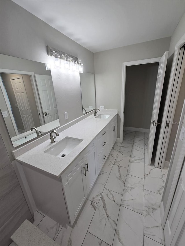 full bathroom with double vanity, marble finish floor, and a sink