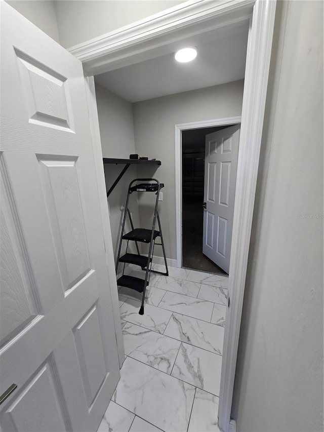 laundry area with marble finish floor and baseboards