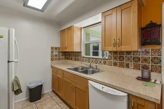 kitchen featuring white appliances, light tile patterned floors, a sink, light countertops, and backsplash