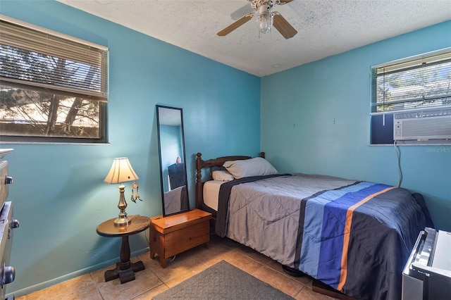 bedroom featuring cooling unit, baseboards, ceiling fan, a textured ceiling, and tile patterned floors