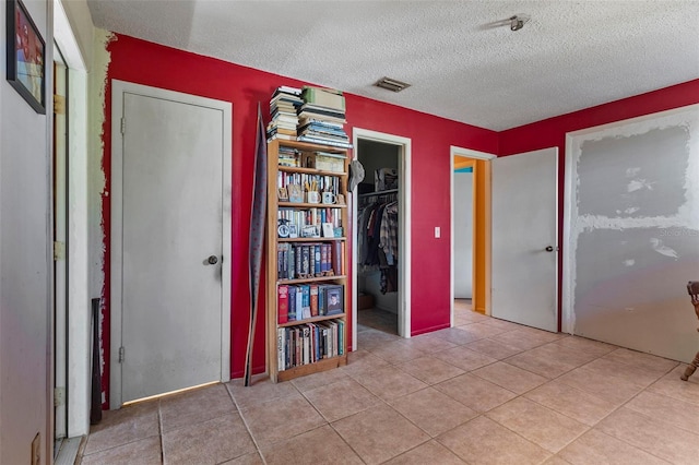 unfurnished bedroom with tile patterned floors, visible vents, and a textured ceiling