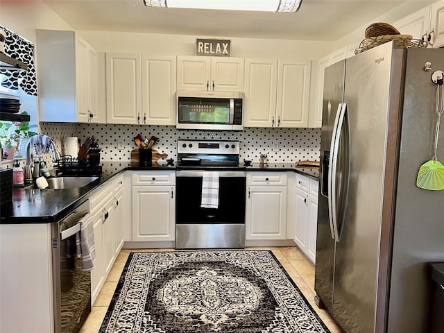 kitchen with light tile patterned floors, a sink, decorative backsplash, stainless steel appliances, and dark countertops