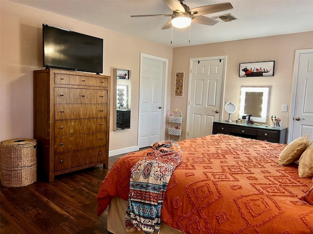 bedroom featuring a ceiling fan, wood finished floors, visible vents, and baseboards