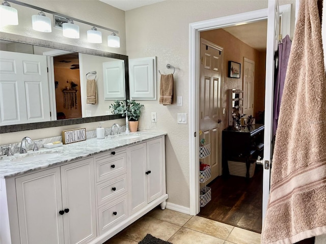 bathroom featuring tile patterned flooring, double vanity, baseboards, and a sink