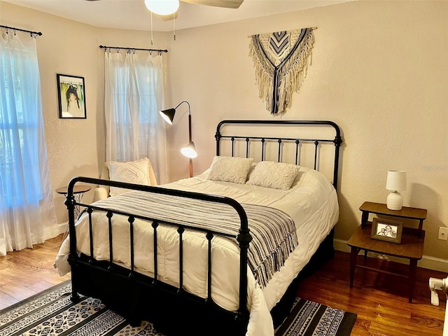 bedroom featuring a ceiling fan, baseboards, and wood finished floors