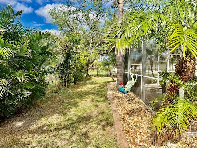 view of yard with glass enclosure and fence