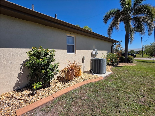 view of side of property featuring central air condition unit, a lawn, and stucco siding