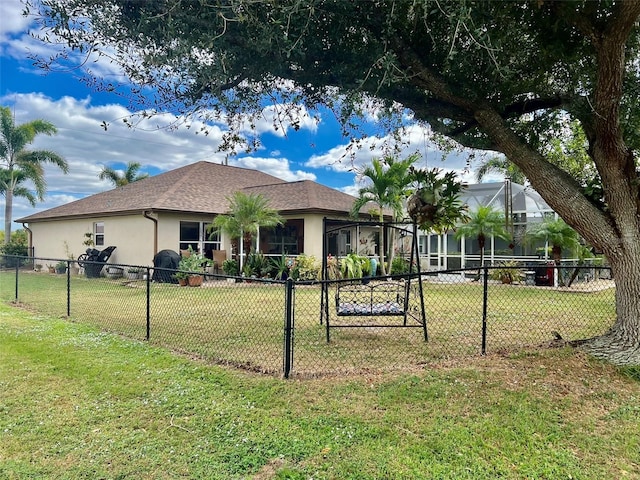 view of front of home with a front lawn, fence, a lanai, and stucco siding