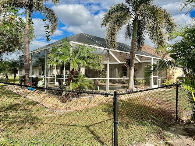 rear view of property with a lanai, fence, and stucco siding