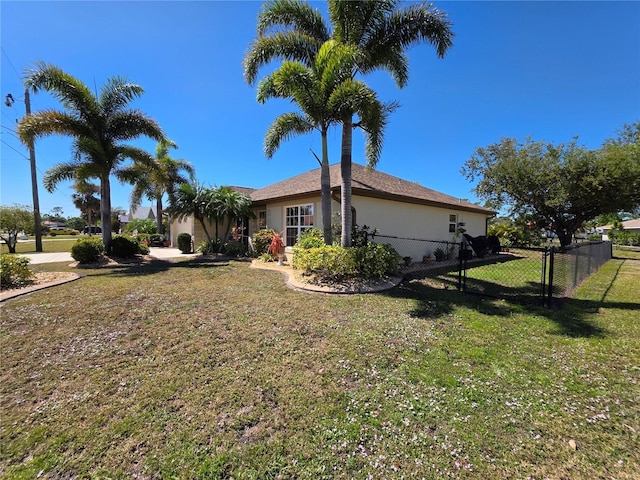 view of side of home with stucco siding, a lawn, and fence