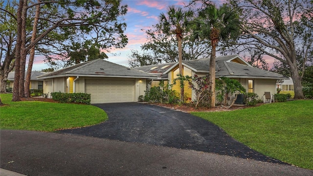 ranch-style house featuring an attached garage, a tile roof, a lawn, stucco siding, and driveway