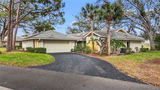 ranch-style home with aphalt driveway, a front lawn, an attached garage, and a tile roof