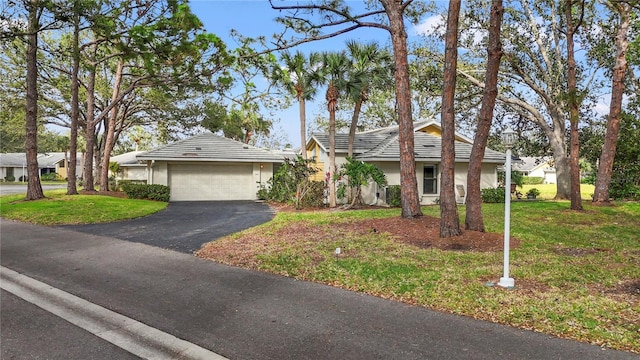 single story home with stucco siding, a tile roof, a detached garage, and a front lawn