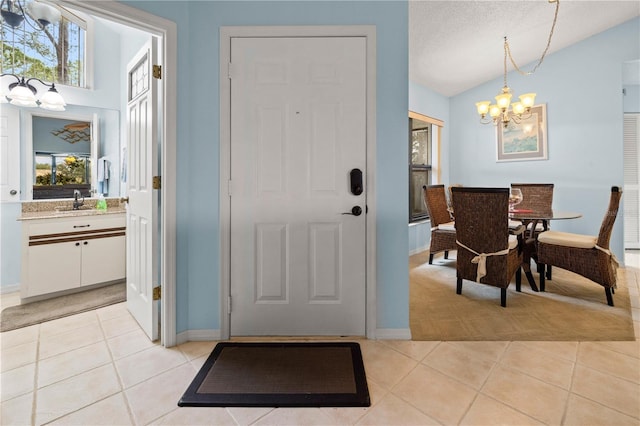 entryway with an inviting chandelier, light tile patterned floors, baseboards, and lofted ceiling