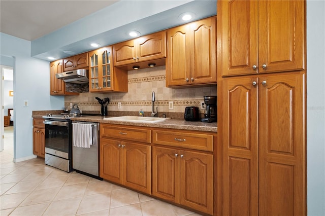 kitchen featuring under cabinet range hood, stainless steel appliances, backsplash, and a sink