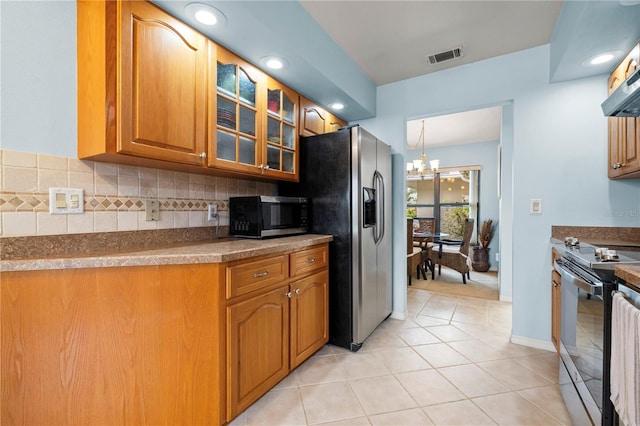 kitchen featuring visible vents, backsplash, glass insert cabinets, brown cabinets, and stainless steel appliances