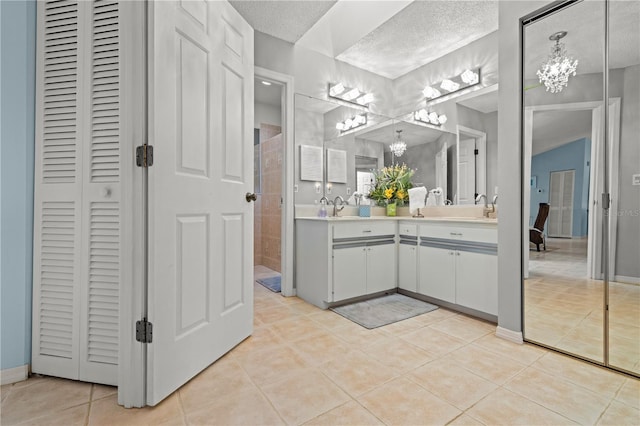 bathroom with tile patterned floors, a notable chandelier, double vanity, and a closet