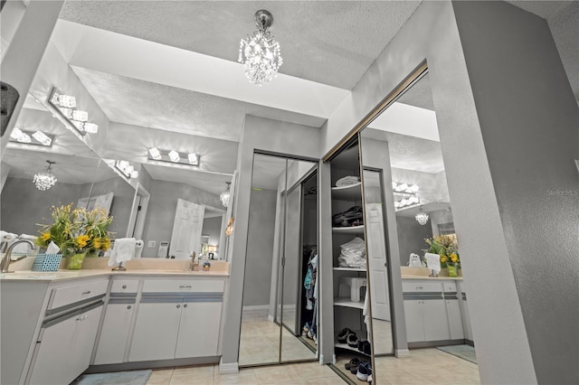 bathroom with tile patterned floors, a notable chandelier, a textured ceiling, and vanity