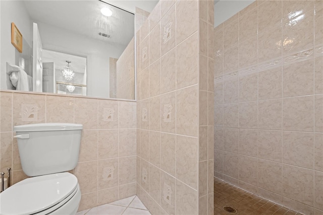 bathroom featuring visible vents, tiled shower, tile walls, toilet, and tile patterned floors