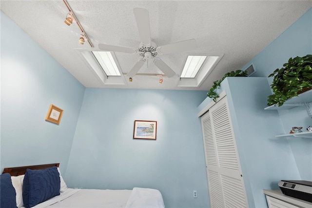 bedroom featuring visible vents, a skylight, a closet, a textured ceiling, and a ceiling fan