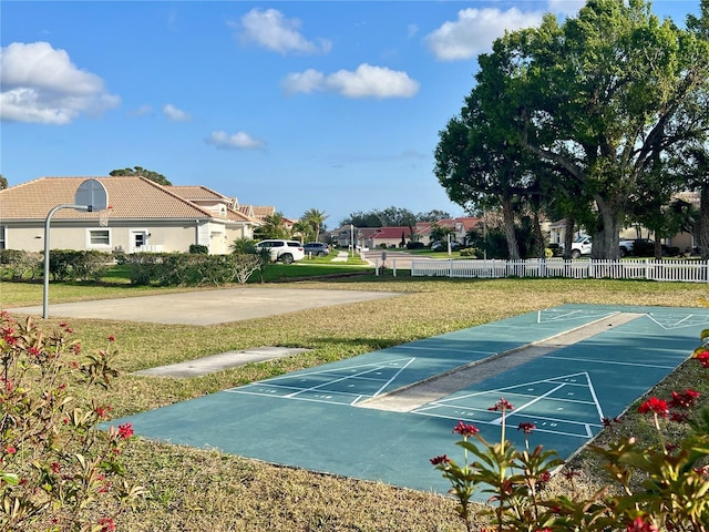 view of home's community featuring shuffleboard, a lawn, and fence