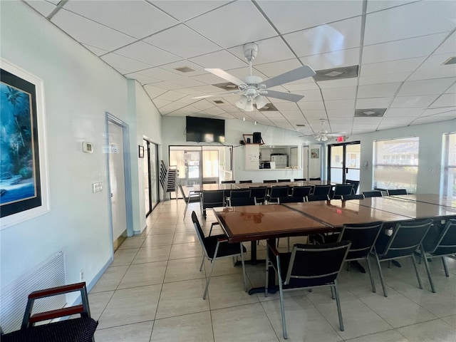 dining room with light tile patterned flooring, a drop ceiling, visible vents, and a ceiling fan