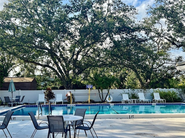 pool featuring outdoor dining area, a patio, and fence