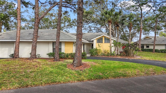 view of front facade with stucco siding, a garage, and a front yard