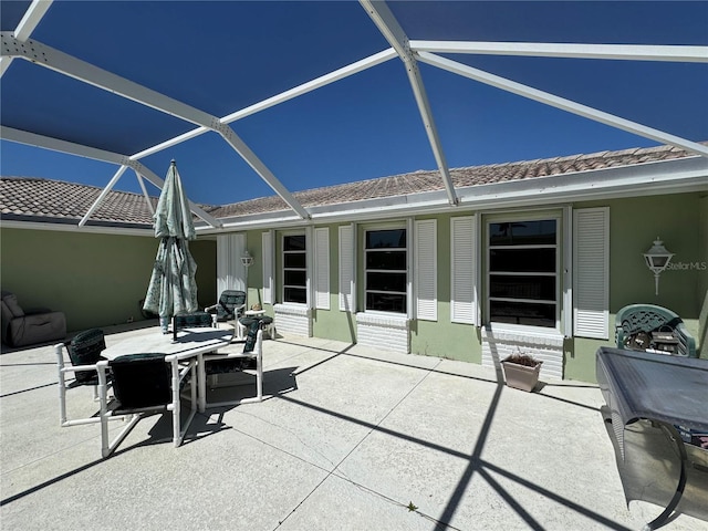 view of patio with glass enclosure and outdoor dining space