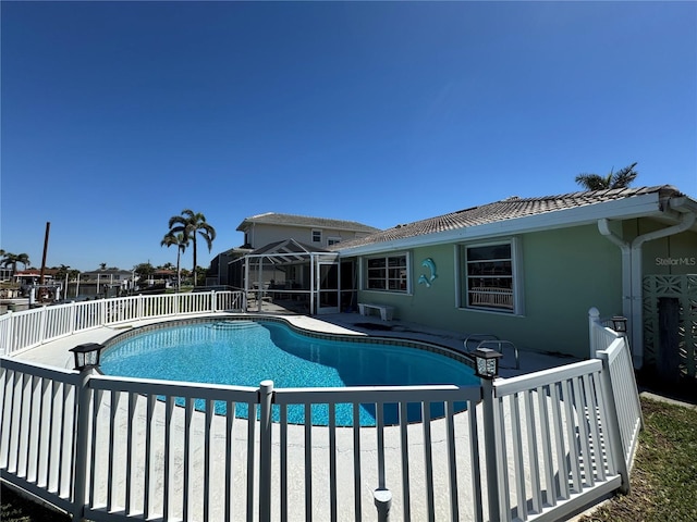 view of swimming pool with glass enclosure, a patio, a fenced in pool, and fence