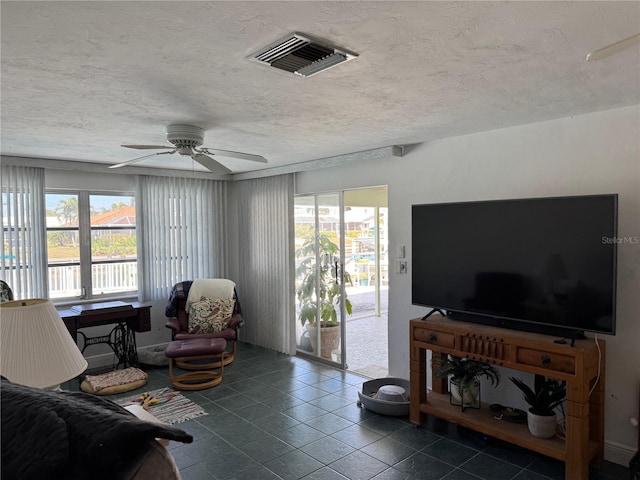 living area featuring visible vents, a textured ceiling, ceiling fan, and dark tile patterned flooring