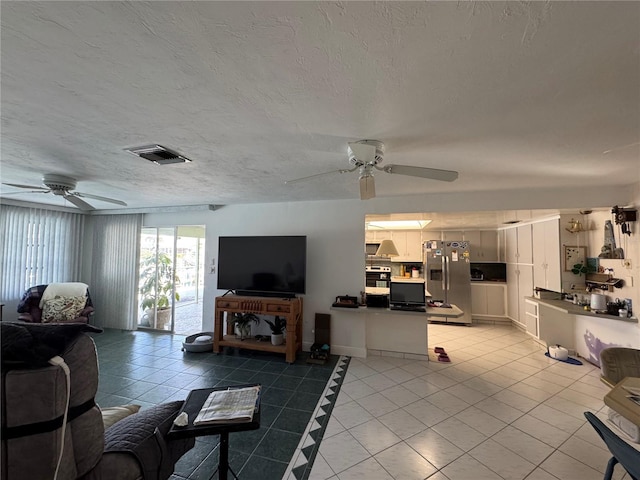 living area with light tile patterned flooring, visible vents, a textured ceiling, and ceiling fan