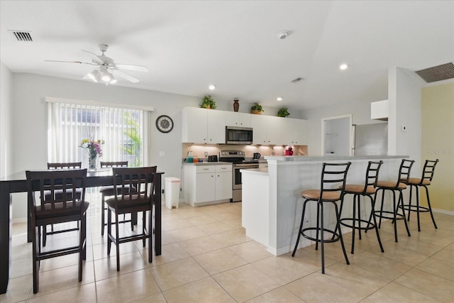 kitchen featuring a ceiling fan, visible vents, a breakfast bar, white cabinets, and appliances with stainless steel finishes