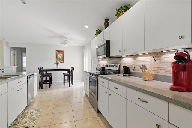 kitchen with backsplash, ceiling fan, light tile patterned floors, stainless steel appliances, and a sink