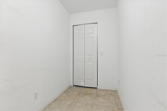 spare room featuring light tile patterned flooring and baseboards