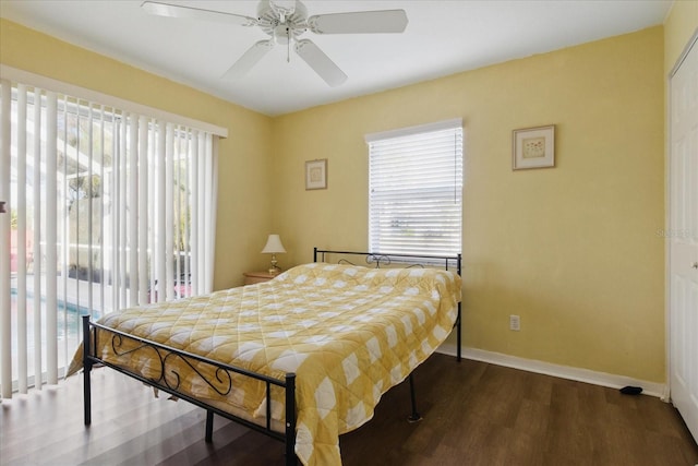 bedroom with baseboards, multiple windows, dark wood-style floors, and access to exterior